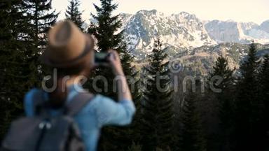 年轻的旅游妇女带着背包<strong>站在山顶</strong>上，欣赏着令人惊叹的景色。 有魅力的女孩拍照片